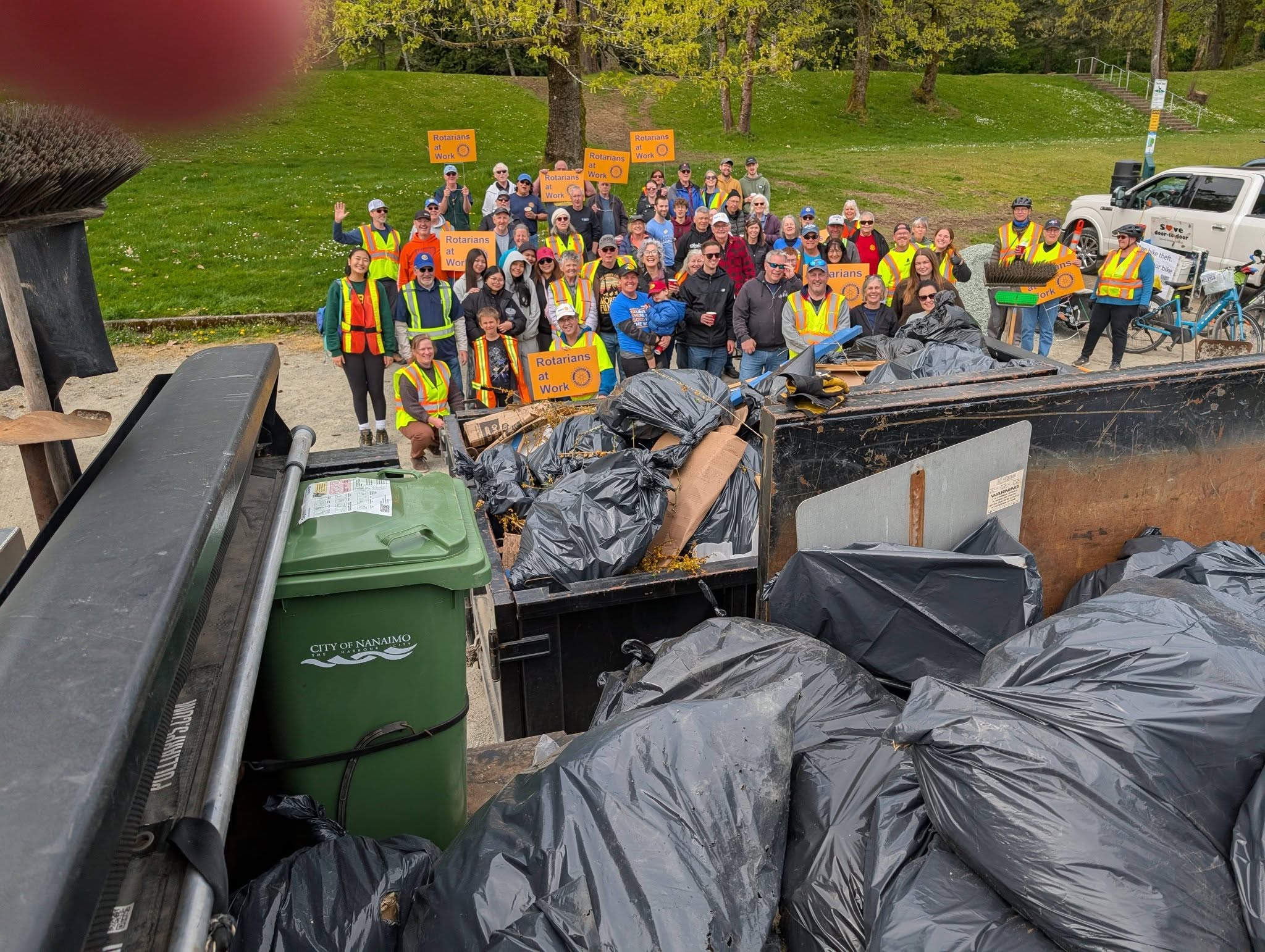 A group of people from the Rotary Clubs of Nanaimo and Lantzville with piles of trash collected for Earth Day 2026