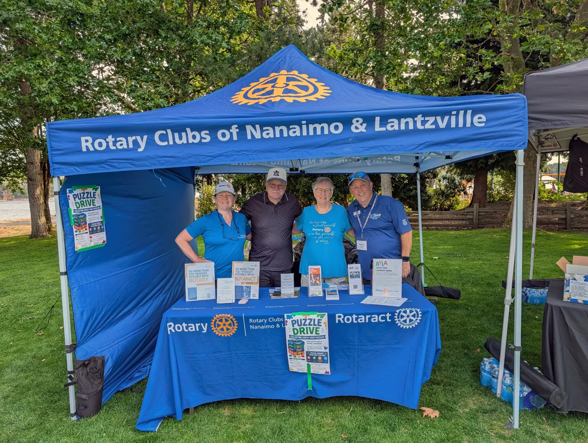 A group of people from local Rotary Clubs standing at a booth at the Silly boat regata